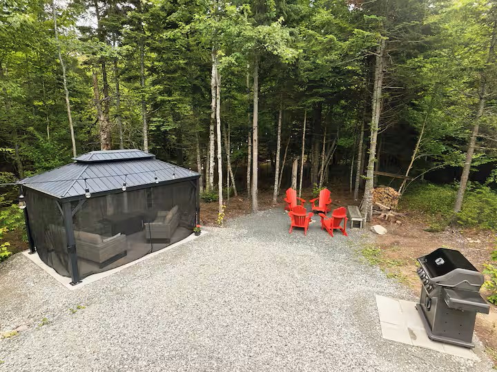 Fire pit with red Adirondack chairs and Napoleon BBQ