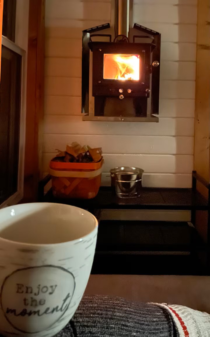 Tiny wood stove glowing with coffee cup in foreground
